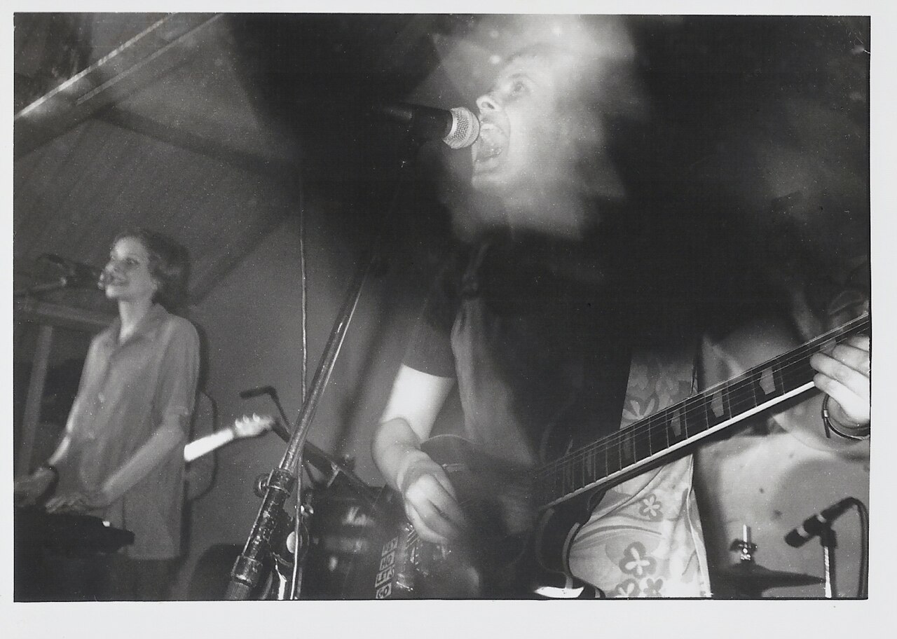 An independent musician performing live in a small, intimate venue, engaging with a focused audience, illustrating grassroots career building.